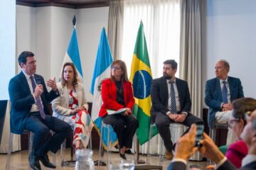 Panel internacional en Guatemala con representantes de Brasil y Guatemala, reunidos en un foro diplomático y energético. Líderes en traje formal dialogan frente a las banderas nacionales, en un ambiente profesional con participación activa del público.