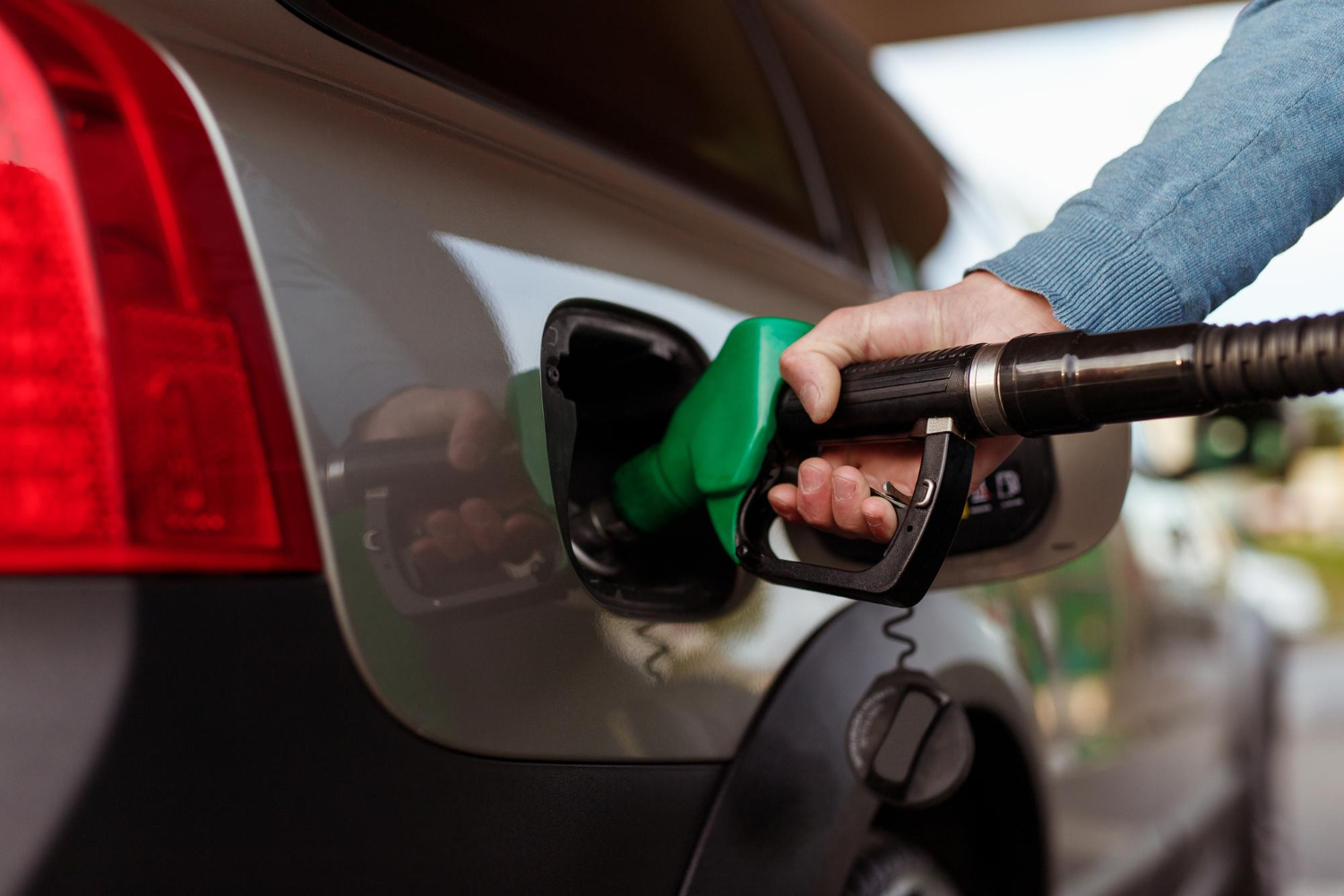 Mano introduce dispensador de gasolina e10 en boquilla de tanque de vehículo